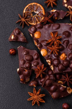 Fındıklı siyah acı çikolata, şekerli meyve ve nane. Koyu beton bir arka planda parçalara ayrılmış.