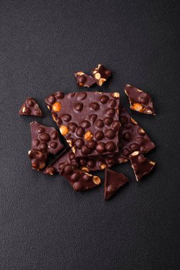 Fındıklı siyah acı çikolata, şekerli meyve ve nane. Koyu beton bir arka planda parçalara ayrılmış.