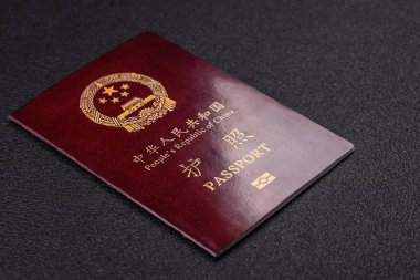 Koyu beton arka planda bir Çin vatandaşının uluslararası pasaportu.