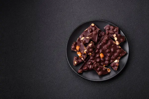 Fındıklı siyah acı çikolata, şekerli meyve ve nane. Koyu beton bir arka planda parçalara ayrılmış.