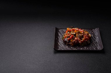 Baharatlı Asya yemeği dilimlenmiş et filetosu, acı biber, havuç ve susam tohumları koyu beton arka planda.