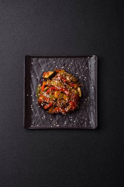 Baharatlı Asya yemeği dilimlenmiş et filetosu, acı biber, havuç ve susam tohumları koyu beton arka planda.