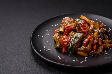 Baharatlı Asya yemeği dilimlenmiş et filetosu, acı biber, havuç ve susam tohumları koyu beton arka planda.