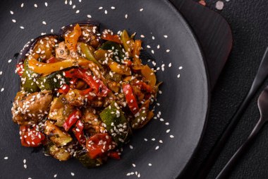 Baharatlı Asya yemeği dilimlenmiş et filetosu, acı biber, havuç ve susam tohumları koyu beton arka planda.