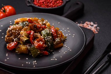 Baharatlı Asya yemeği dilimlenmiş et filetosu, acı biber, havuç ve susam tohumları koyu beton arka planda.