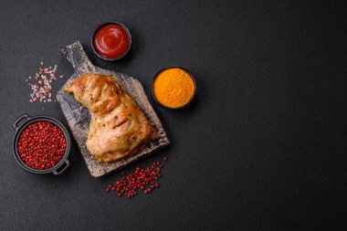 Lezzetli ızgara tavuk budu ya da koyu beton arka planda tuz ve baharatlı çeyreklik.