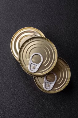 Yuvarlak metal teneke kutu konserve et ya da anahtar ile koyu beton arka planda açmak için balık.