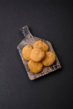 Yuvarlak balık veya tuzlu tavuk nuggetları ve koyu beton arka planda ekilmiş baharatlar.