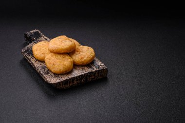 Yuvarlak balık veya tuzlu tavuk nuggetları ve koyu beton arka planda ekilmiş baharatlar.