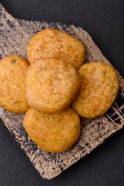 Yuvarlak balık veya tuzlu tavuk nuggetları ve koyu beton arka planda ekilmiş baharatlar.