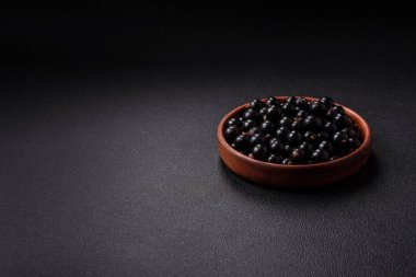 Olgun kuşüzümü, koyu beton arka planda seramik bir kasede su damlacıkları içinde.