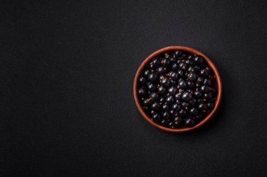 Olgun kuşüzümü, koyu beton arka planda seramik bir kasede su damlacıkları içinde.