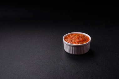 Kırmızı acı ya da baharatlı biberli, domatesli, sarımsaklı, baharatlı ve otlu koyu beton arka planda.