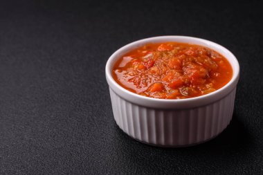 Kırmızı acı ya da baharatlı biberli, domatesli, sarımsaklı, baharatlı ve otlu koyu beton arka planda.