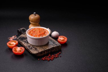 Kırmızı acı ya da baharatlı biberli, domatesli, sarımsaklı, baharatlı ve otlu koyu beton arka planda.