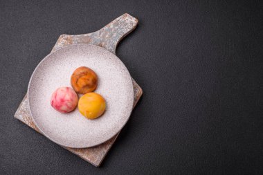 Lezzetli Asya mochi tatlısı pirinç hamuru kabuğu ve koyu beton arka planda meyveler.