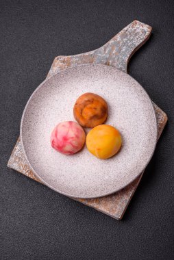 Lezzetli Asya mochi tatlısı pirinç hamuru kabuğu ve koyu beton arka planda meyveler.