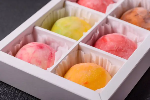 stock image Delicious colorful asian mochi sweets with rice dough shell and fruit filling on dark concrete background