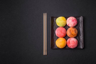 Lezzetli Asya mochi tatlısı pirinç hamuru kabuğu ve koyu beton arka planda meyveler.