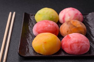 Lezzetli Asya mochi tatlısı pirinç hamuru kabuğu ve koyu beton arka planda meyveler.