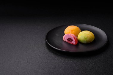 Lezzetli Asya mochi tatlısı pirinç hamuru kabuğu ve koyu beton arka planda meyveler.