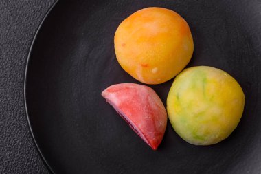 Lezzetli Asya mochi tatlısı pirinç hamuru kabuğu ve koyu beton arka planda meyveler.