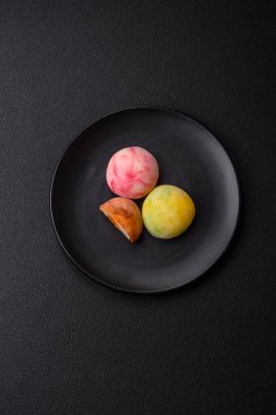 Lezzetli Asya mochi tatlısı pirinç hamuru kabuğu ve koyu beton arka planda meyveler.