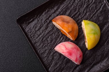 Lezzetli Asya mochi tatlısı pirinç hamuru kabuğu ve koyu beton arka planda meyveler.