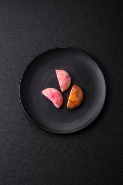 Lezzetli Asya mochi tatlısı pirinç hamuru kabuğu ve koyu beton arka planda meyveler.