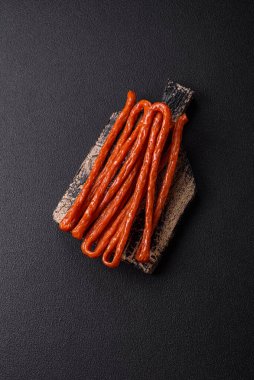 Koyu beton bir zeminde tuz ve baharatla tütsülenmiş mini sosis ya da kababanosi.