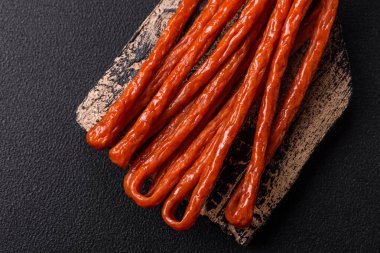 Koyu beton bir zeminde tuz ve baharatla tütsülenmiş mini sosis ya da kababanosi.