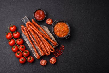 Koyu beton bir zeminde tuz ve baharatla tütsülenmiş mini sosis ya da kababanosi.