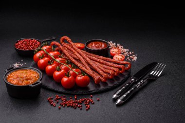 Koyu beton bir zeminde tuz ve baharatla tütsülenmiş mini sosis ya da kababanosi.