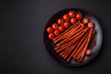 Koyu beton bir zeminde tuz ve baharatla tütsülenmiş mini sosis ya da kababanosi.