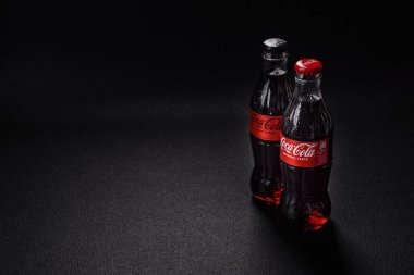 Nikopol, Dnepropetrovsk bölgesi / Ukrayna - 15 Temmuz 2024: Siyah zemin üzerinde su damlaları bulunan bir şişe soğutulmuş koka-kola. Sıcak bir yaz gününde serin bir içecek.