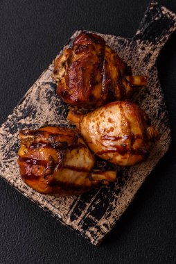Lezzetli ızgara tavuk bacağı. Baharatlı ve otlu teriyaki soslu. Koyu beton arka planda.