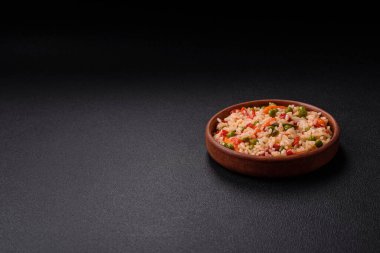 Lezzetli haşlanmış pirinç, sebzeli havuç, bezelye, tuz ve baharatla birlikte koyu beton arka planda.