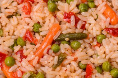 Lezzetli haşlanmış pirinç, sebzeli havuç, bezelye, tuz ve baharatla birlikte koyu beton arka planda.