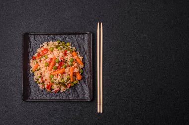 Lezzetli haşlanmış pirinç, sebzeli havuç, bezelye, tuz ve baharatla birlikte koyu beton arka planda.