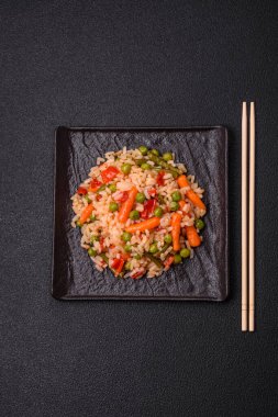 Lezzetli haşlanmış pirinç, sebzeli havuç, bezelye, tuz ve baharatla birlikte koyu beton arka planda.