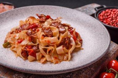 Sebzeli, etli, tuzlu ve baharatlı nefis Asya udonu tabağı koyu beton arka planda seramik bir tabakta.