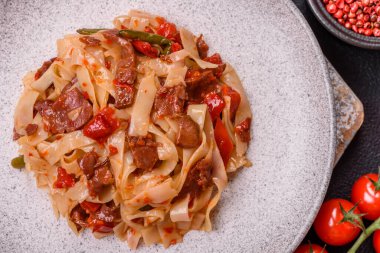 Sebzeli, etli, tuzlu ve baharatlı nefis Asya udonu tabağı koyu beton arka planda seramik bir tabakta.