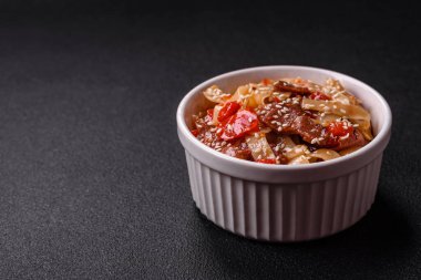 Sebzeli, etli, tuzlu ve baharatlı nefis Asya udonu tabağı koyu beton arka planda seramik bir tabakta.