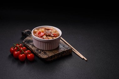 Sebzeli, etli, tuzlu ve baharatlı nefis Asya udonu tabağı koyu beton arka planda seramik bir tabakta.