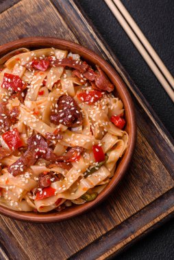 Sebzeli, etli, tuzlu ve baharatlı nefis Asya udonu tabağı koyu beton arka planda seramik bir tabakta.