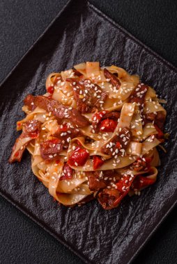 Sebzeli, etli, tuzlu ve baharatlı nefis Asya udonu tabağı koyu beton arka planda seramik bir tabakta.