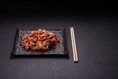 Sebzeli, etli, tuzlu ve baharatlı nefis Asya udonu tabağı koyu beton arka planda seramik bir tabakta.