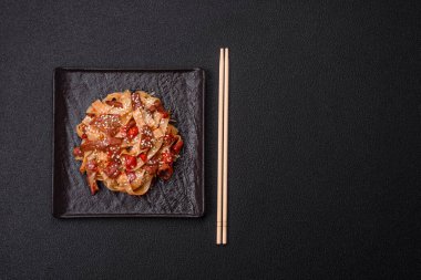 Sebzeli, etli, tuzlu ve baharatlı nefis Asya udonu tabağı koyu beton arka planda seramik bir tabakta.