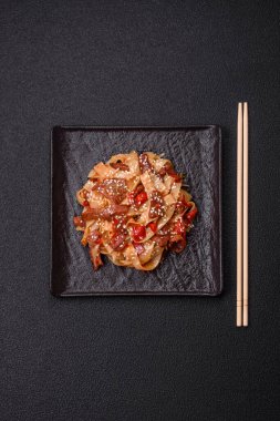 Sebzeli, etli, tuzlu ve baharatlı nefis Asya udonu tabağı koyu beton arka planda seramik bir tabakta.