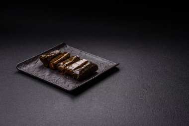 Pirinç şeklinde lezzetli dolma ve üzüm yapraklarına sarılmış et veya tuz ve baharatla değiştirilmiş et.